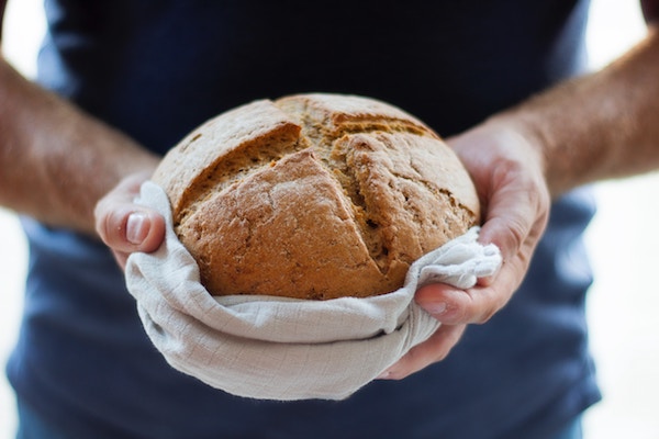 Baked holding fresh-baked loaf of bread