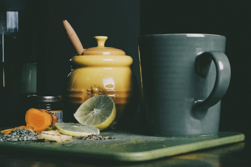 Fresh turmeric on a cutting board with a lemon, honey and a mug